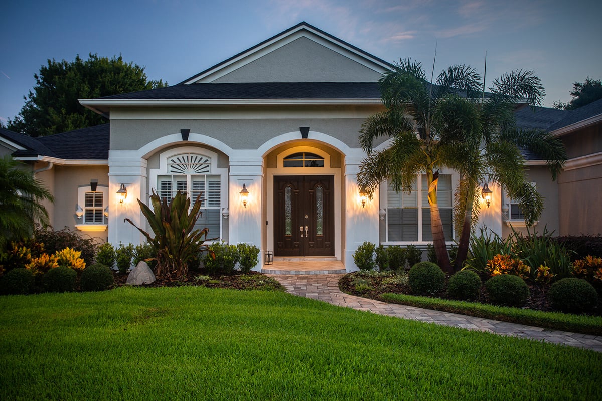 landscape lighting on palm trees at entrance to home