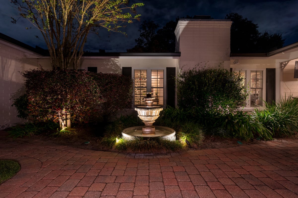 landscape lighting around fountain at entrance of home