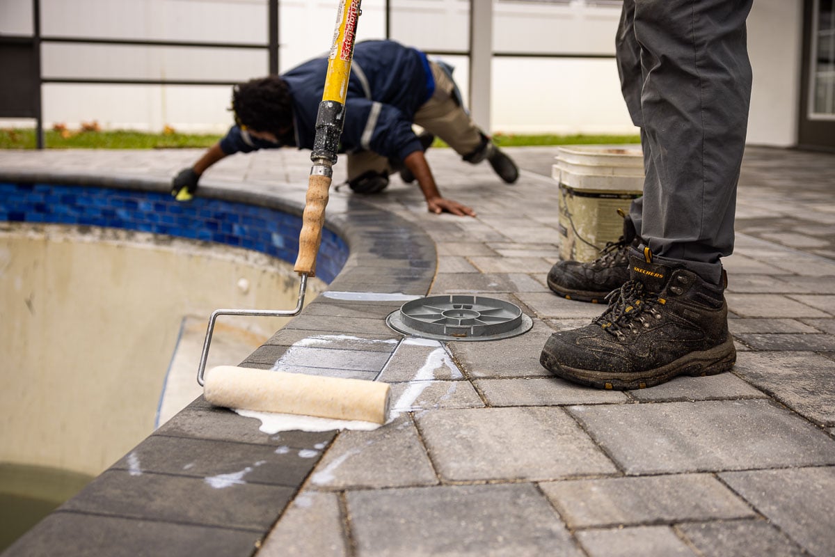 landscape crew sealing a paver pool deck