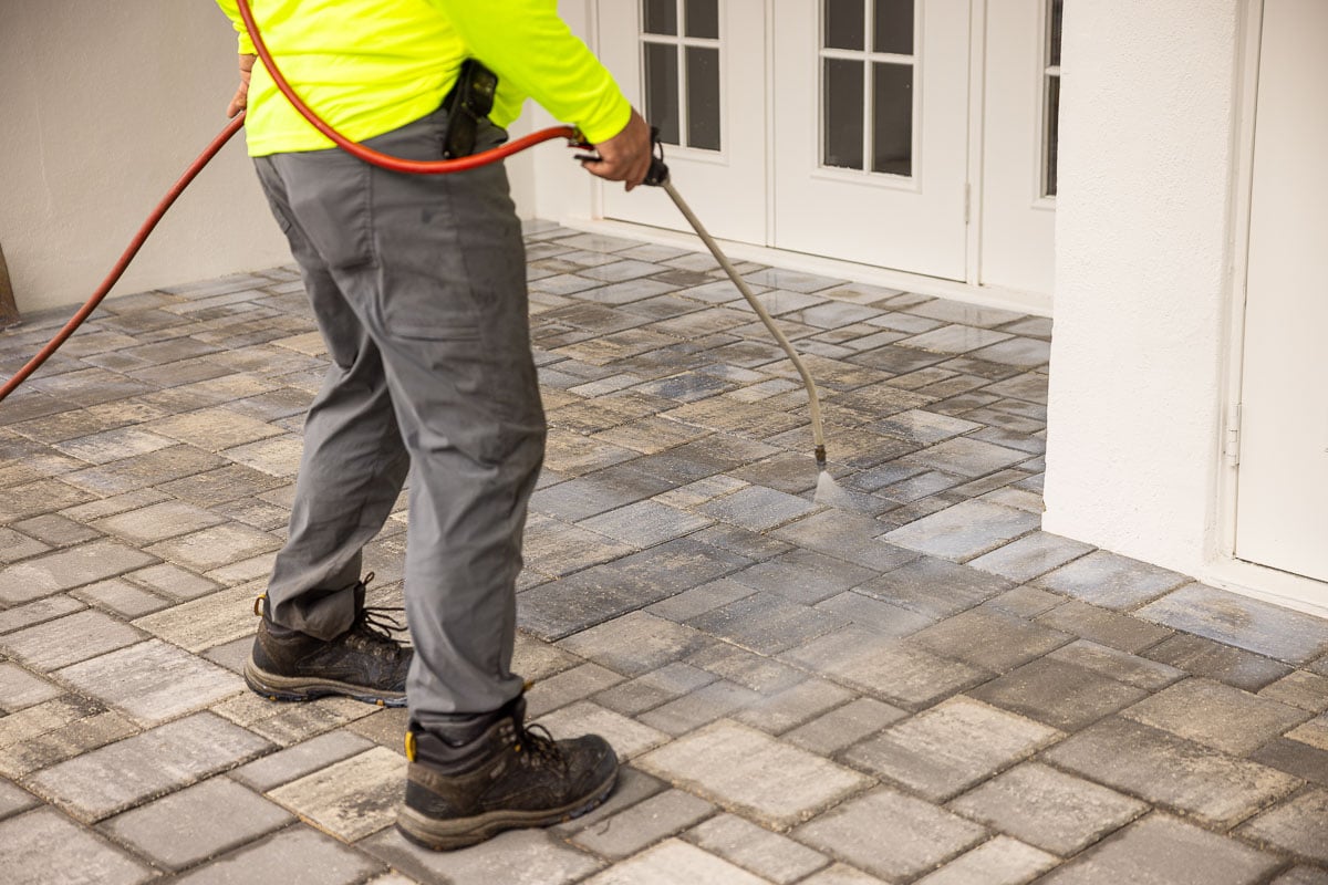 hardscape crew member sealing a paver patio