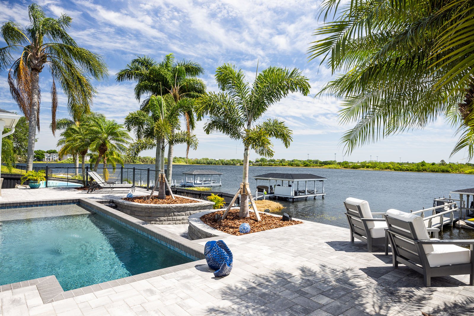 hardscape pavers pool decking with palm trees outdoor furniture waterfront view
