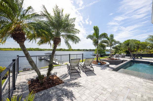 hardscape pavers pool decking with palm trees outdoor furniture waterfront view