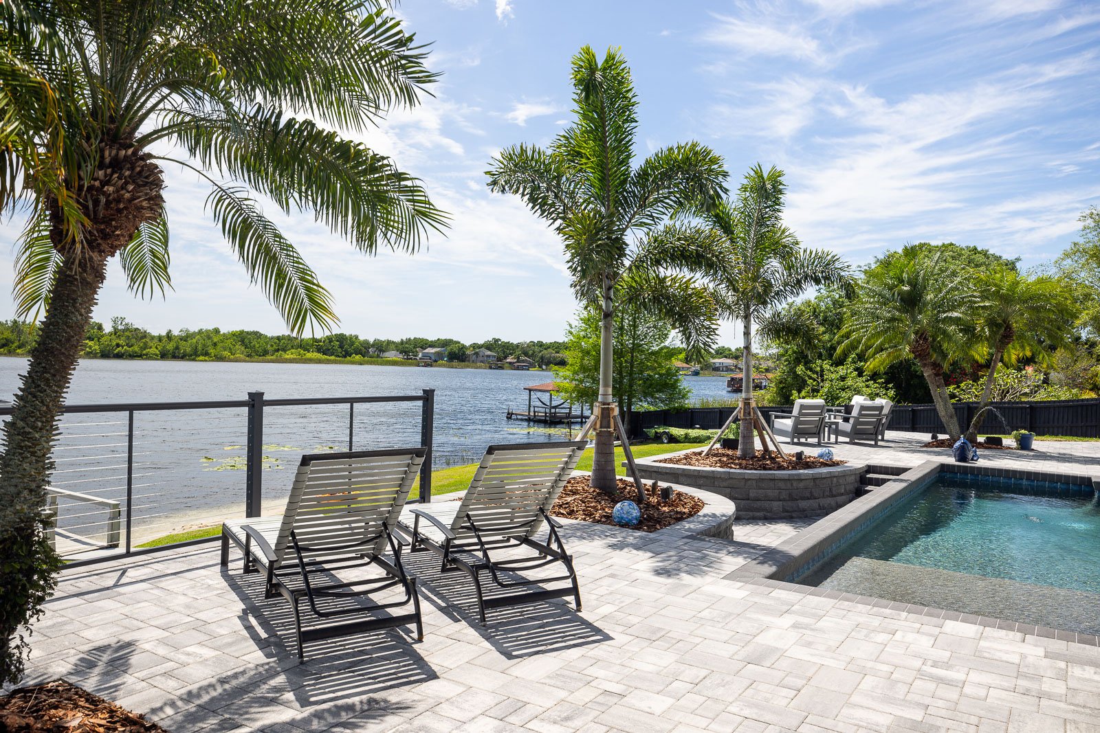hardscape pavers pool decking with palm trees outdoor furniture waterfront view 2