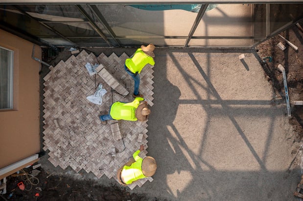 hardscape installation crew installing a basketweave paver patio 