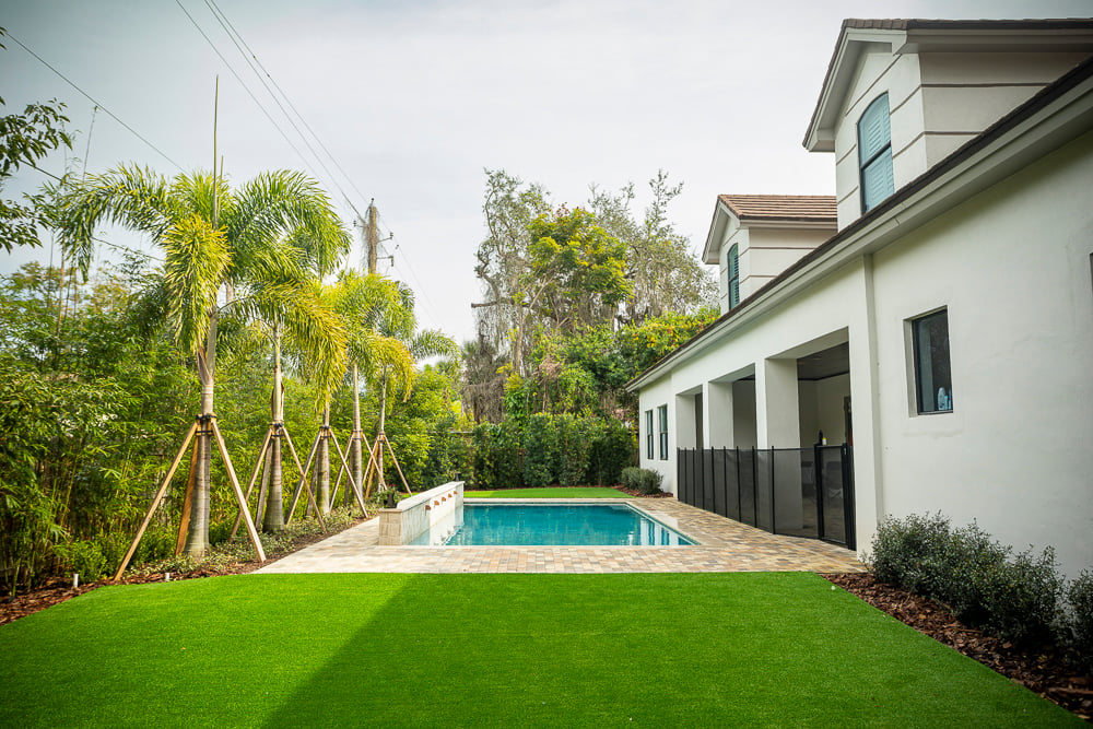 artificial turf near pool with patio and palm trees