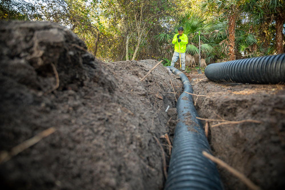 landscape crew installs drain pipe