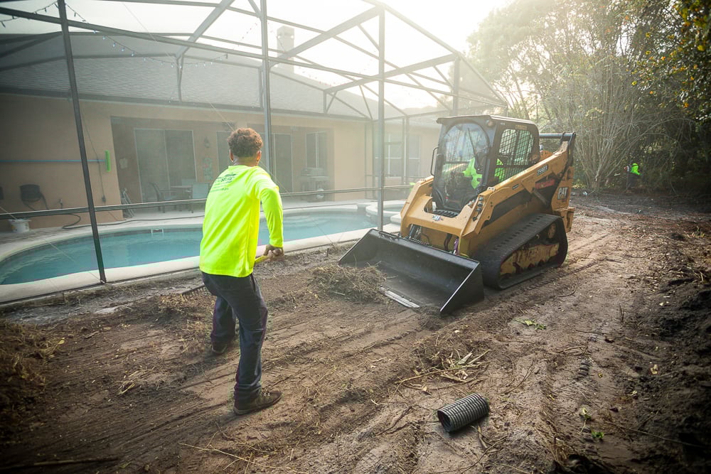 landscape technicians preparing a lawn for sod installation with heavy equipment