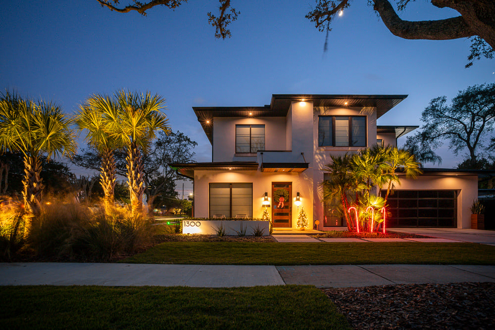 landscape lighting in front yard of a house with lawn and palm trees