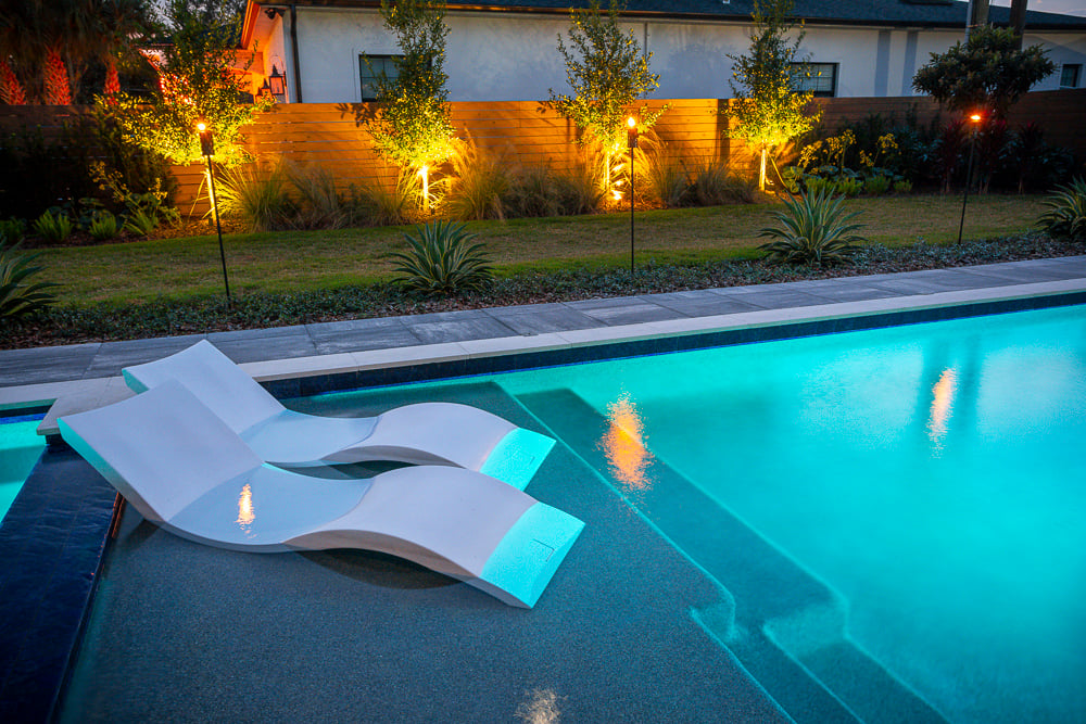 pool with recliners and landscape lighting