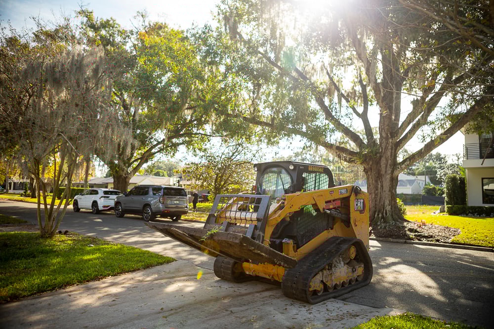 skid loader on a driveway during landscape installation