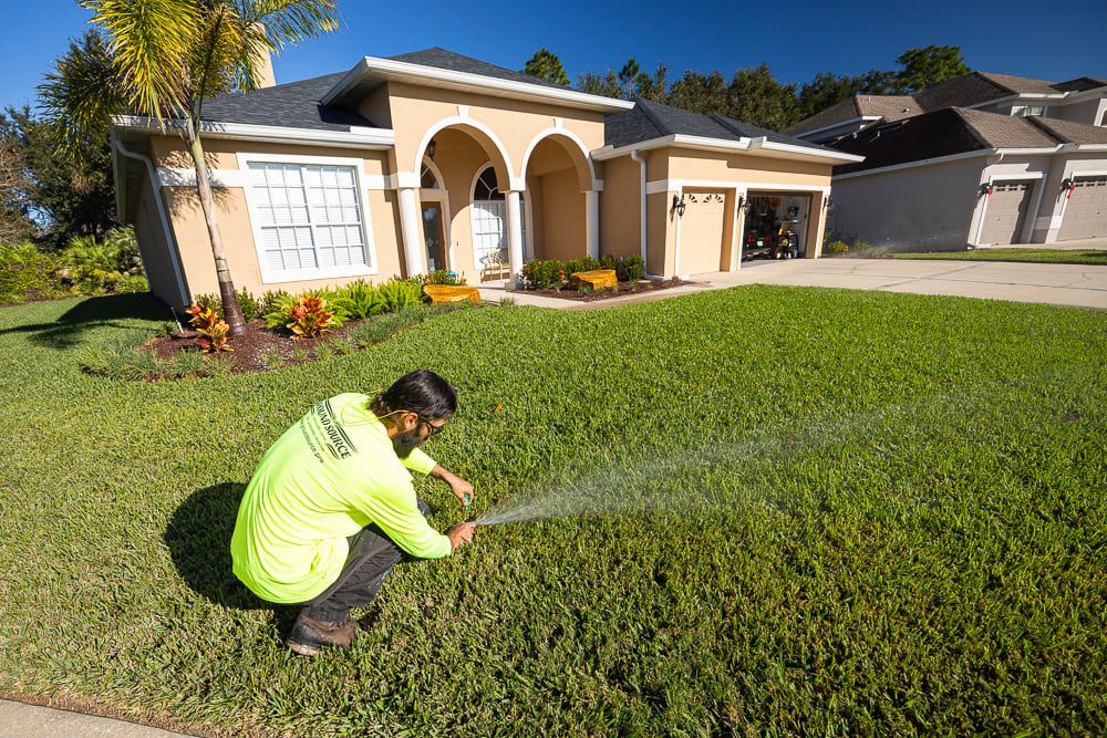irrigation technician calibrating a sprinkler head in a lawn