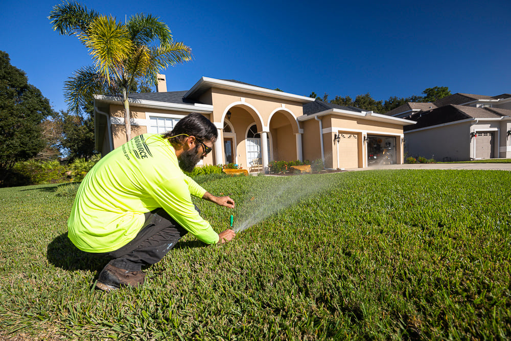 irrigation technician calibrating a new lawn sprinkler system in yard
