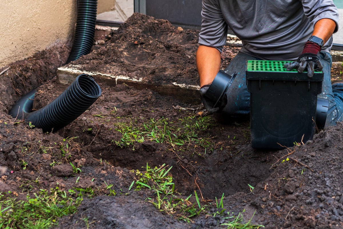 french drain installation in muddy backyard