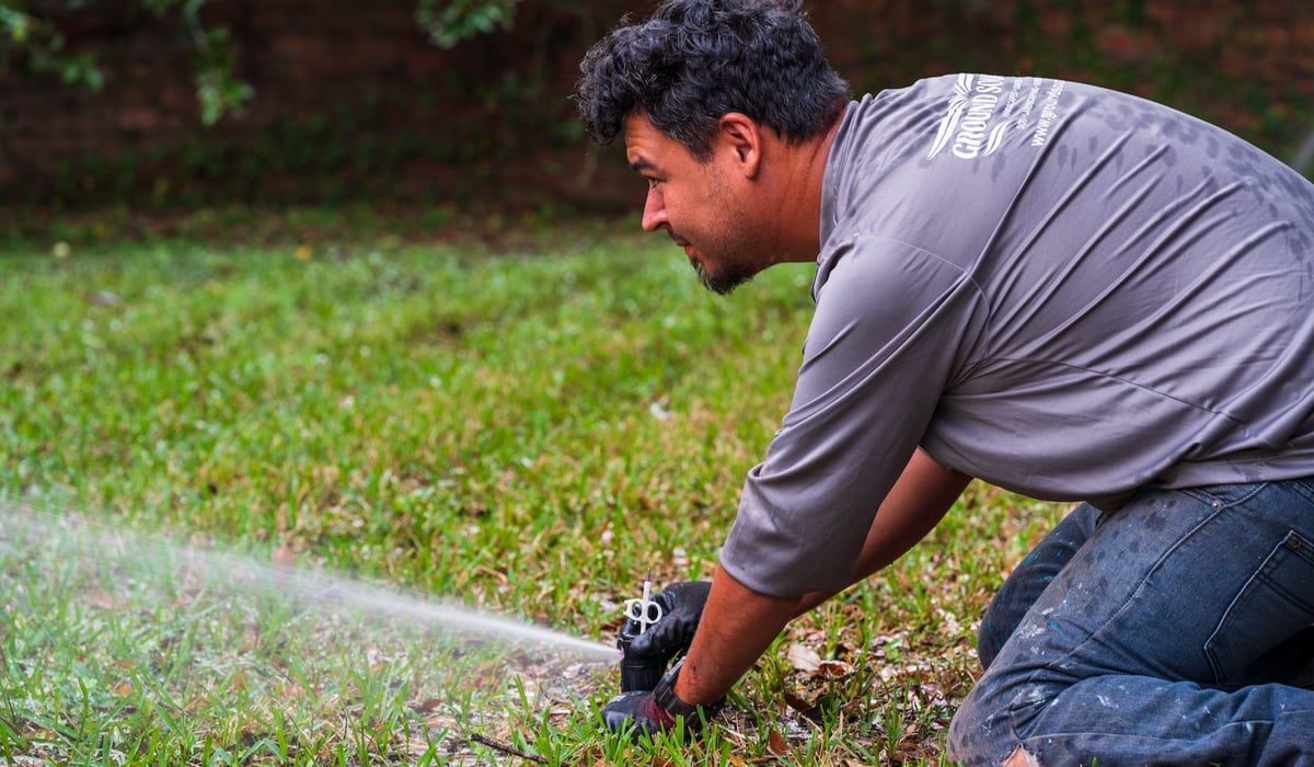 irrigation technician adjusts sprinkler head