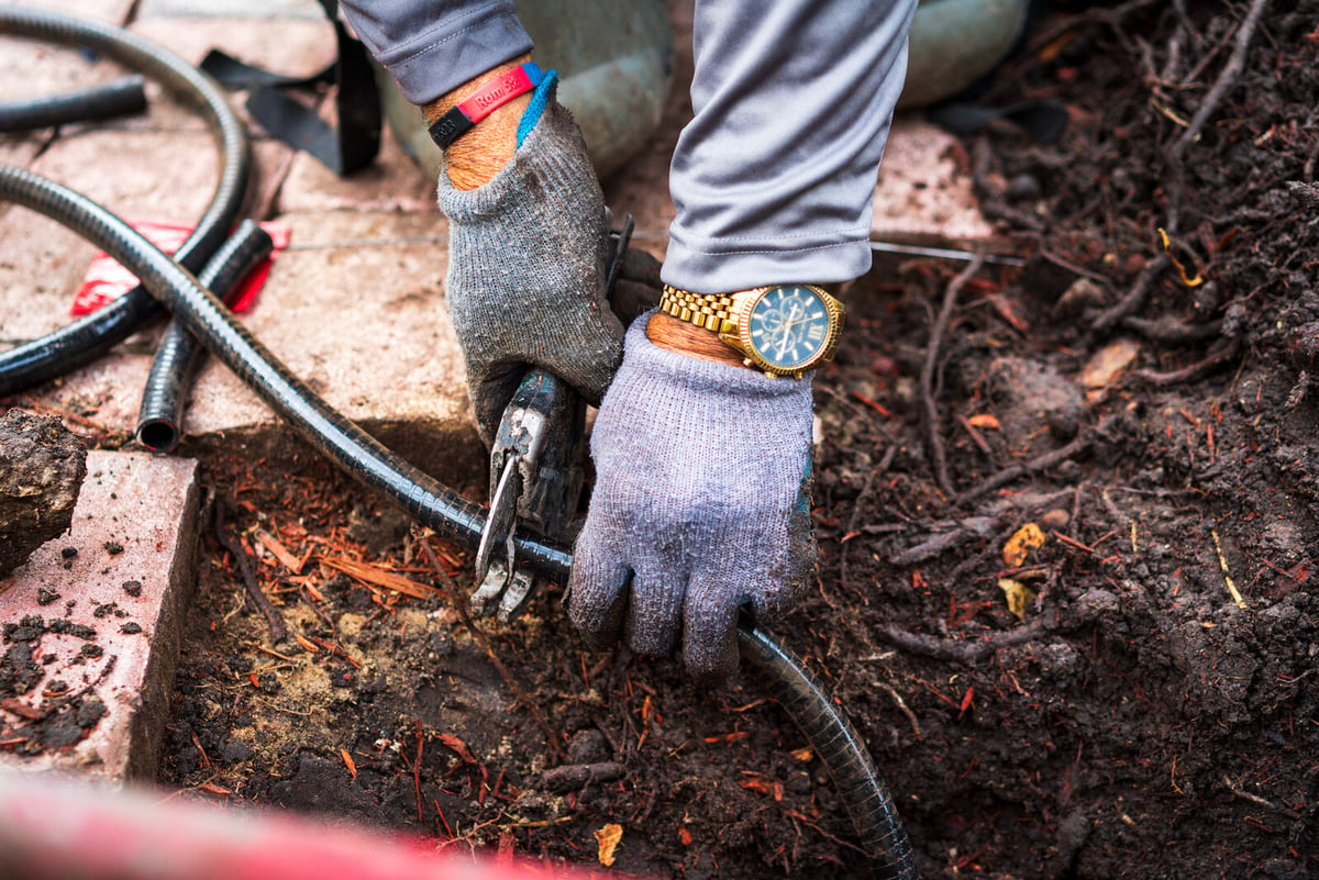 irrigation crew member makes repair to broken sprinkler line