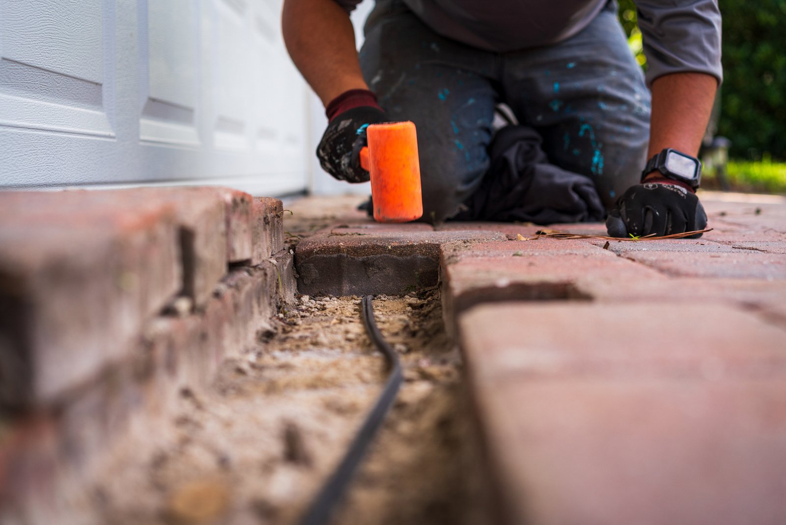 hardscape team member installing a paver sidewalk edge