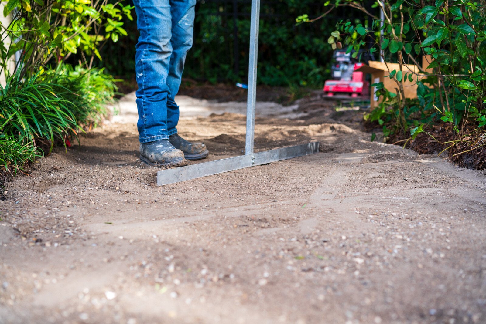 hardscape installation crew member leveling base material for a paver walkway