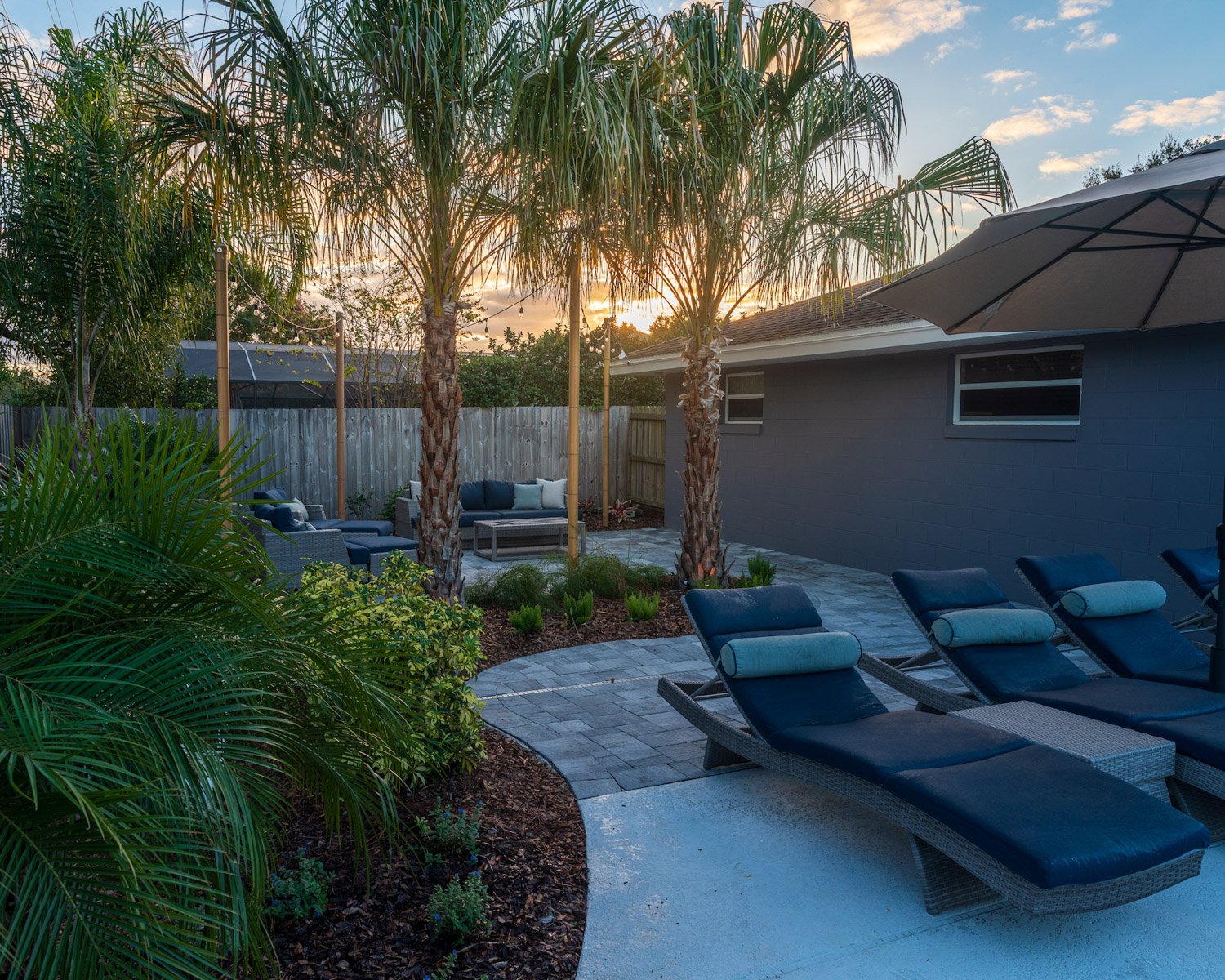 lounge chairs paver patio palm trees plants