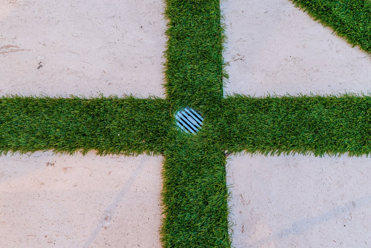 drainage system installed into artificial grass between pavers