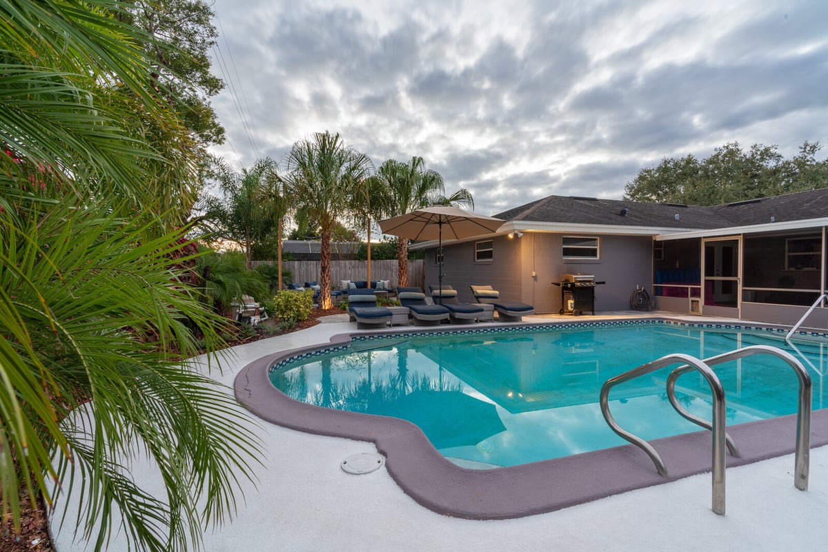 concrete around pool with landscaping and loungers