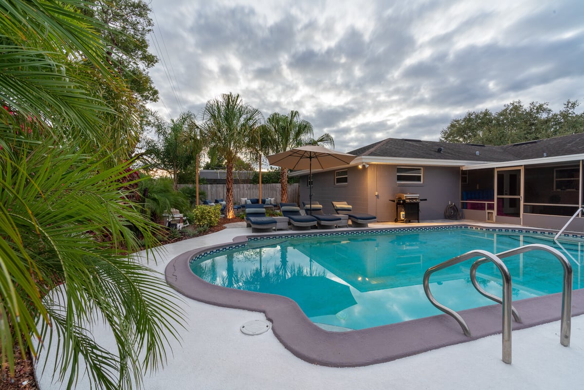 concrete around pool with landscaping and loungers