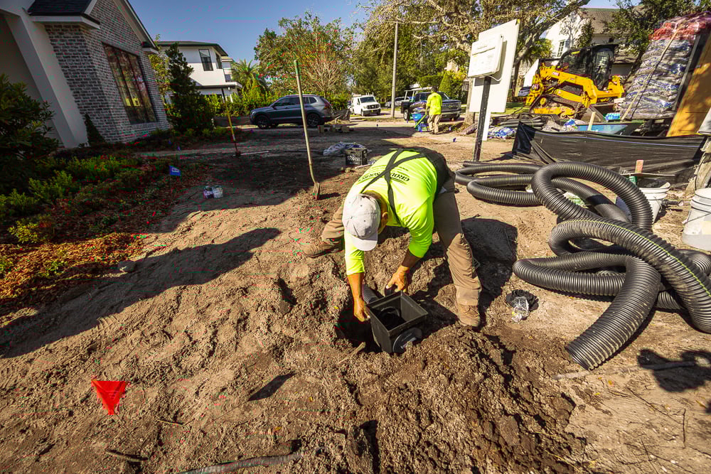 landscape installation team installing french drain and yard drainage boxes in a central florida lawn