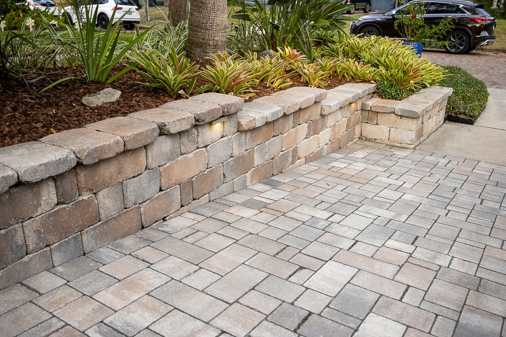 paver driveway with retaining wall and tropical planting beds
