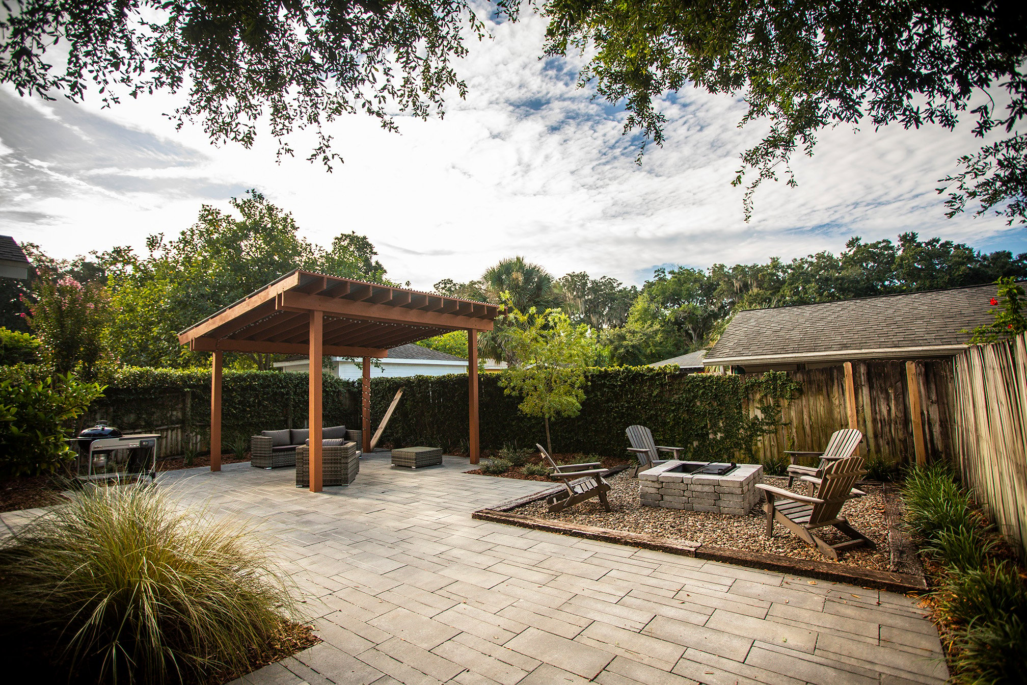 backyard with paver patio plantings fire pit and pergola