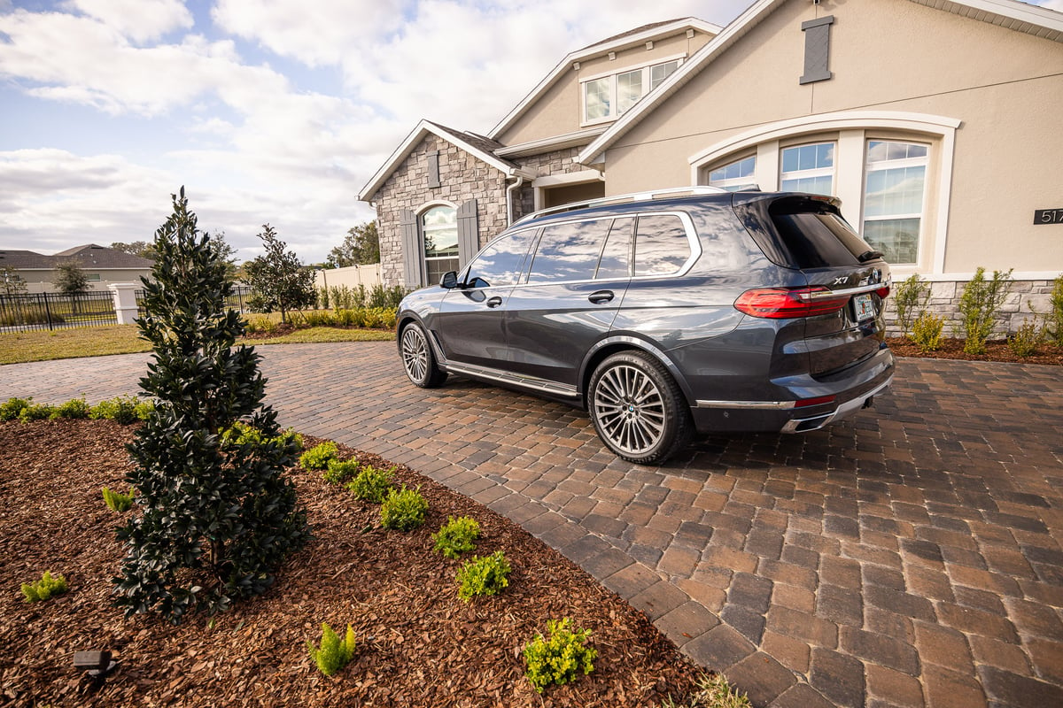 car parked on paver driveway near plantings