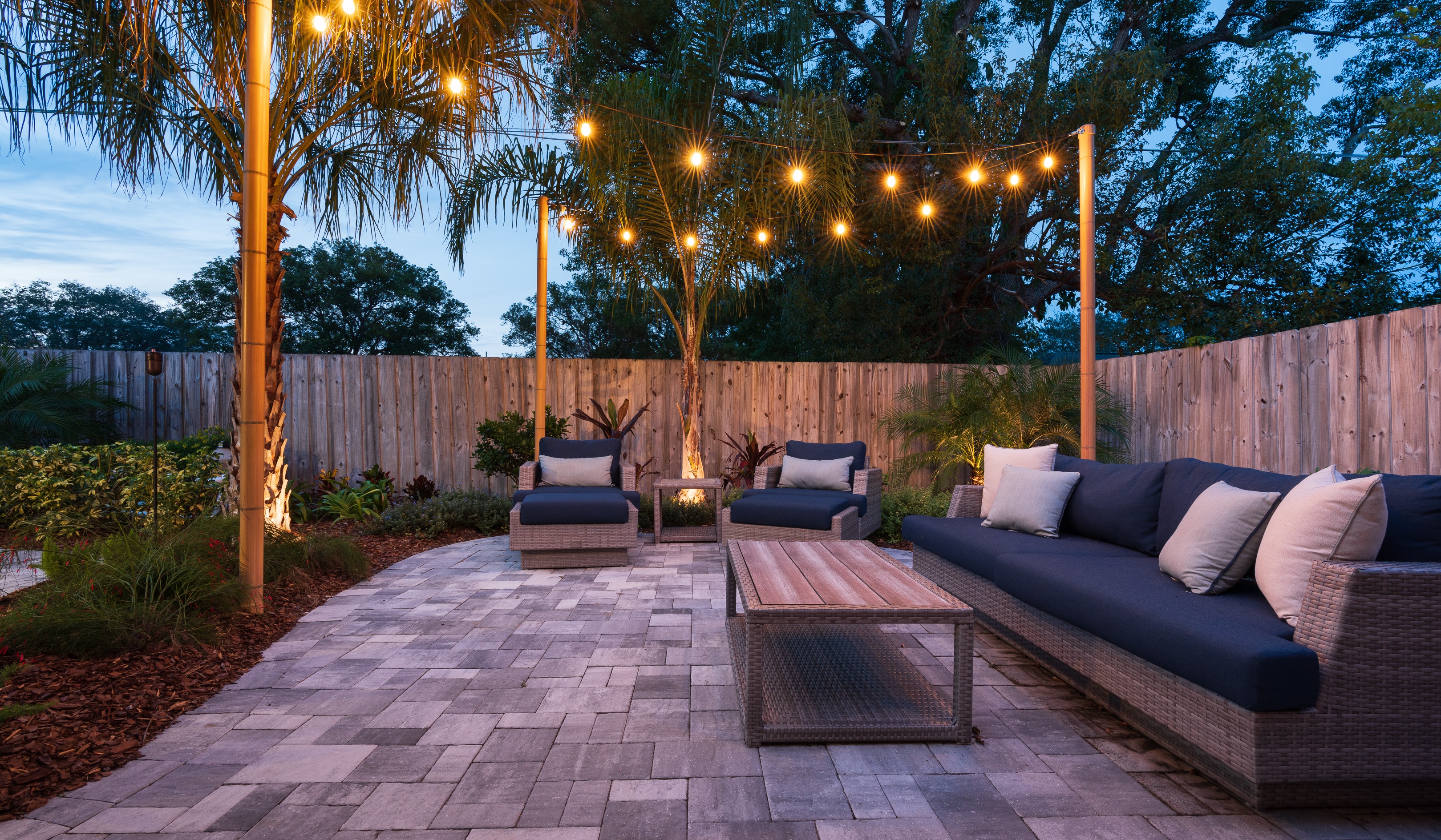string lights and landscape lighting on trees around patio