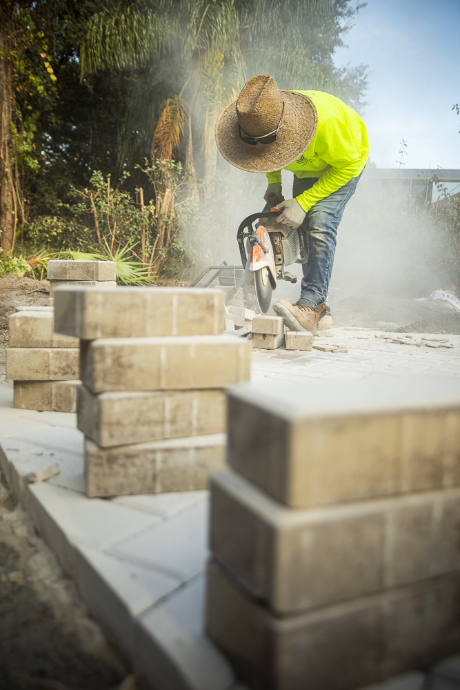 hardscape technician cutting concrete pavers with a cut saw