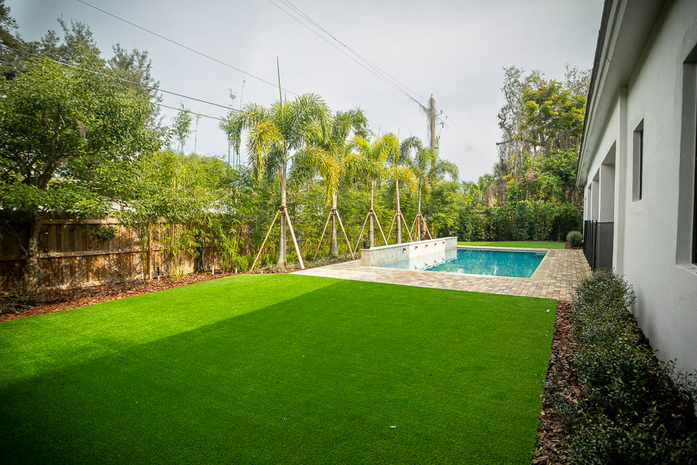 artificial turf in backyard with pool and palm trees