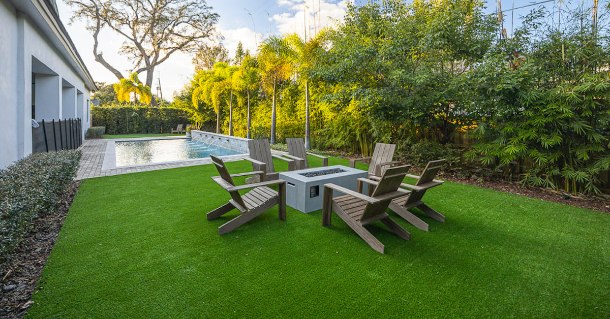 florida backyard with artificial turf, outdoor furniture, plantings and a pool