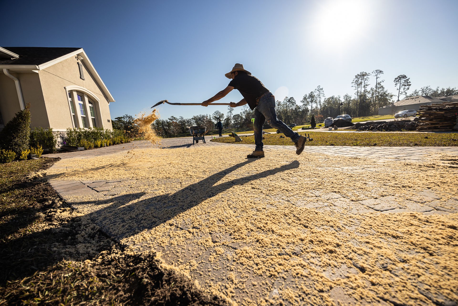 landscaper spreading joint sand on a paver driveway in orlando