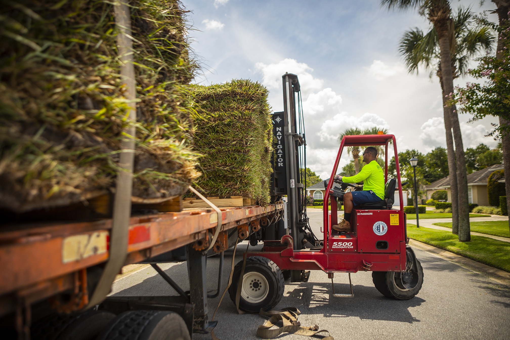 sod delivery being unloaded from a flatbed truck with a forklift